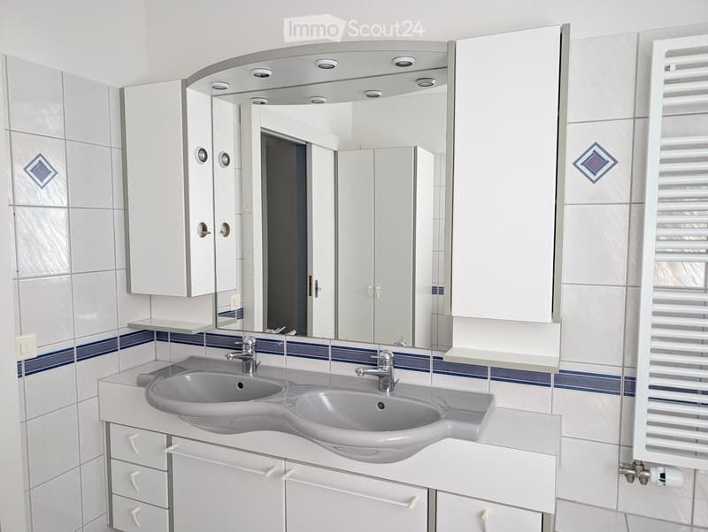 Modern bathroom with white tiles, double sink, mirrored cabinet, and built-in storage.