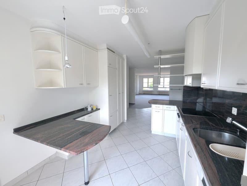 Modern kitchen with white cabinets, dark countertops, and a central island. Features include a sink, faucet, and small decorative items on the counter.