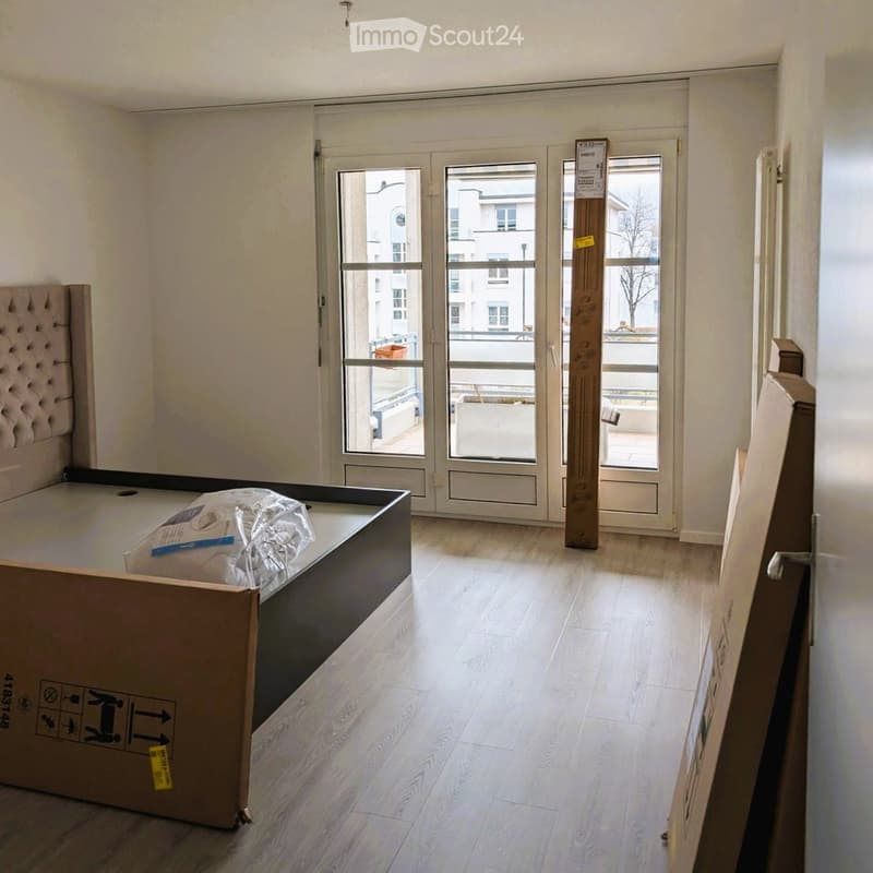 Empty room with wooden flooring, large windows, and a view of the balcony area. No furniture or equipment is present.
