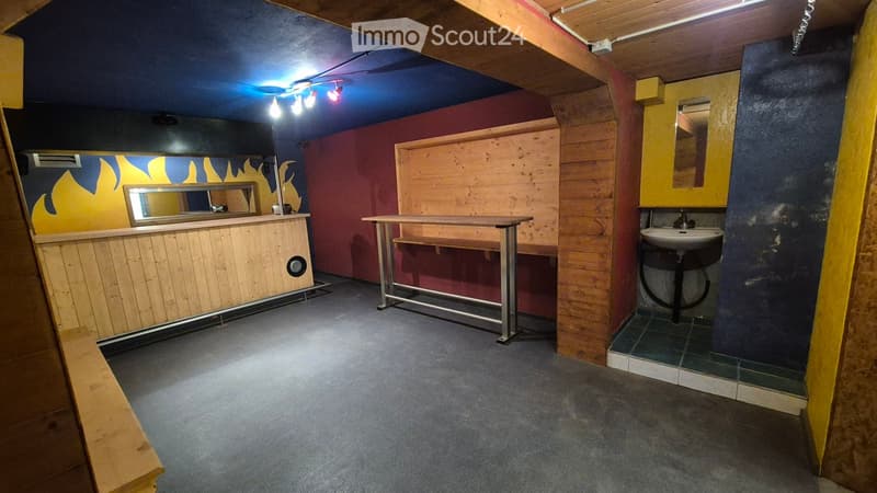 A small, modern room with exposed wooden beams, a sink, a table, and mirrors on the walls.
