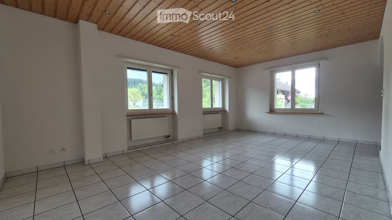 Empty room with tiled floor, wooden ceiling, and multiple windows with radiators below. No furniture or equipment present.