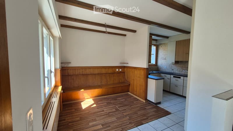 The room features wooden paneling, a bench, a refrigerator, and a small kitchen area with cabinets, a sink, and a dishwasher.