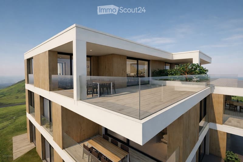 Modern two-story building with large balconies, wooden decking, and glass railings, overlooking a scenic landscape.