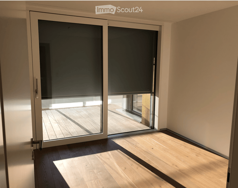 Empty room with wooden flooring and large sliding glass doors leading to a wooden deck area.