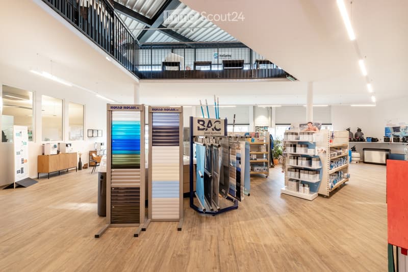 Modern showroom with wooden flooring, display stands for pool systems, shelves with products, a small seating area with a chair and table, and a vase on a side table.