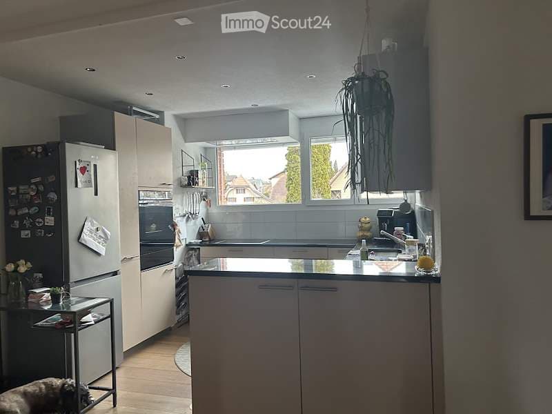 Modern kitchen with white cabinets, stainless steel appliances, island countertop, and large windows overlooking a view.