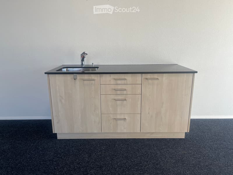 Modern kitchen island with light wood cabinets, stainless steel sink, and faucet.