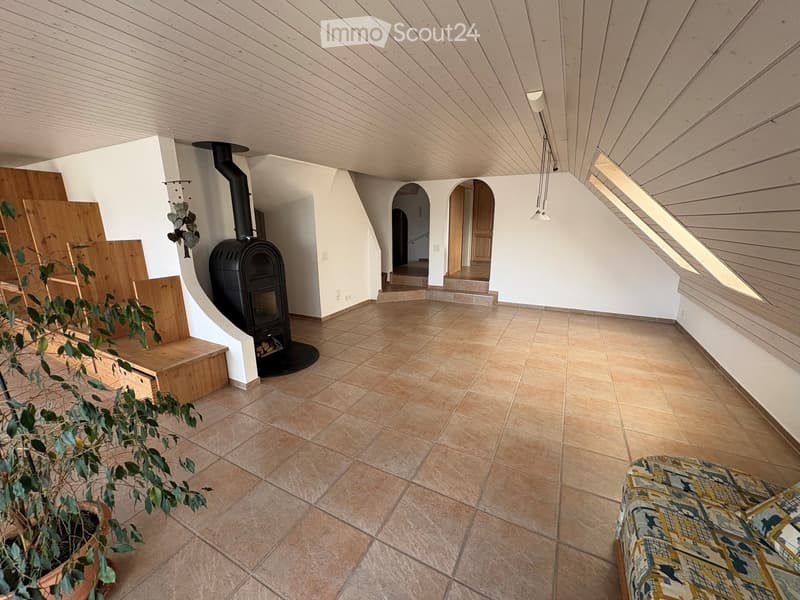 Living room with a tiled floor, wooden ceiling, fireplace, and a patterned sofa.