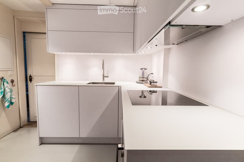 Modern kitchen with white cabinets, a central island, a sink, and a coffee maker on the counter.