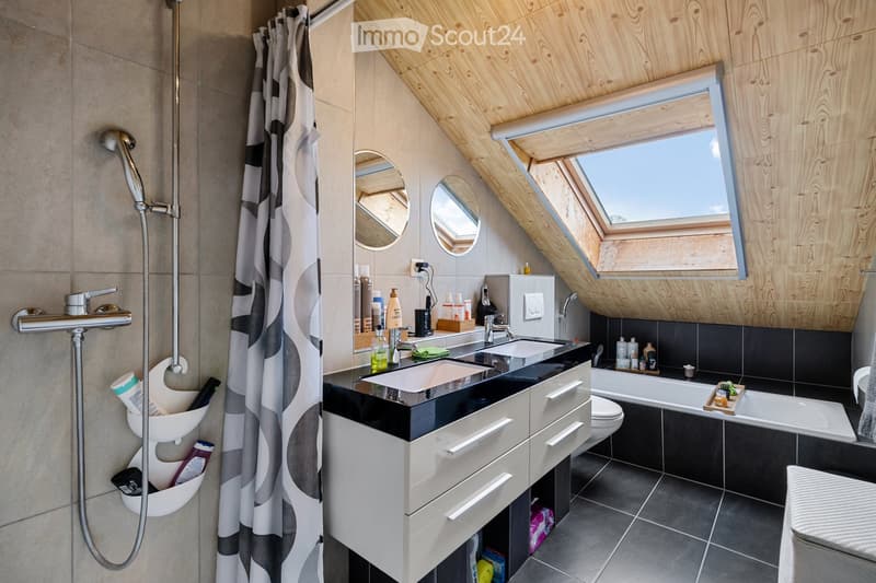 bathroom with slanted ceiling, bathtub, sink with mirror, toilet, skylight