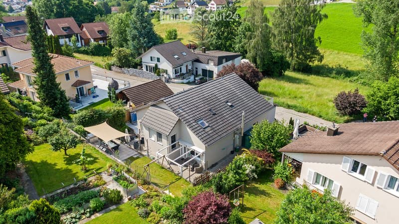 Group of three houses with gardens and a car in front of them.