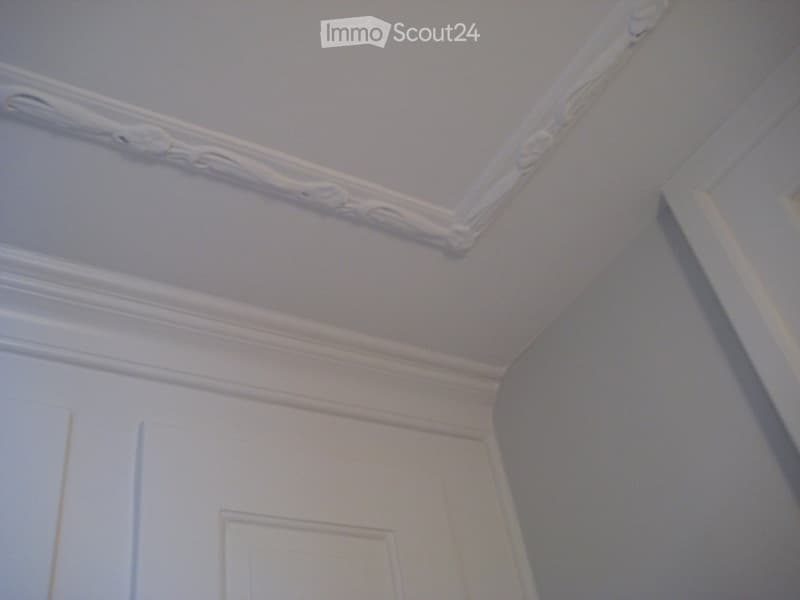 white ceiling with decorative molding, white walls, white door