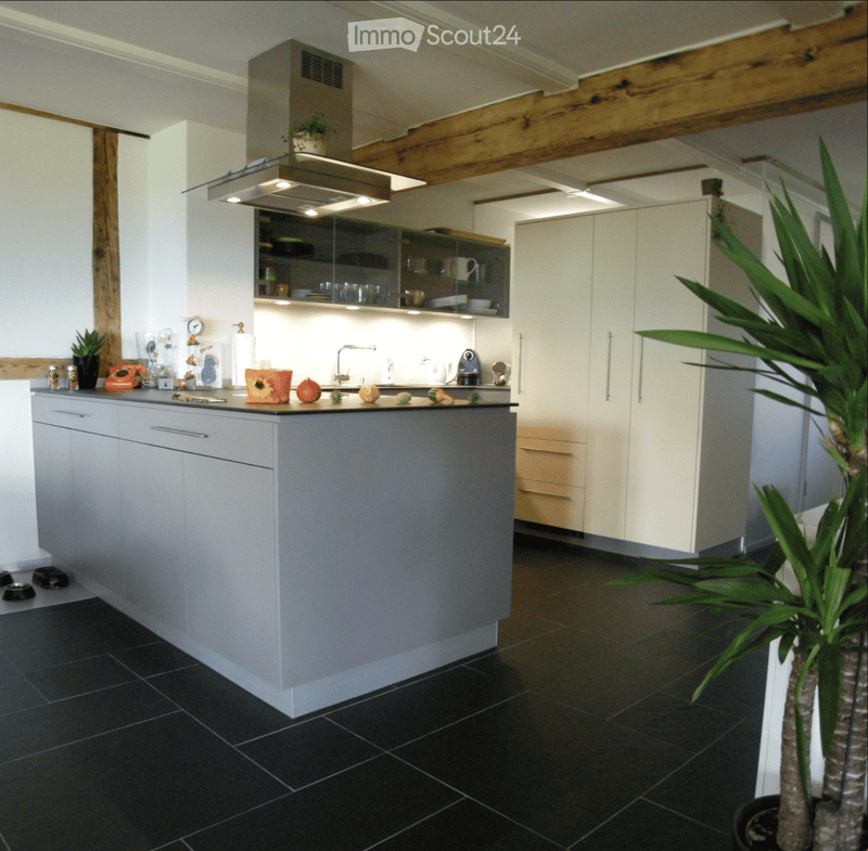 Modern kitchen with grey island, white cabinets, black tiled floor, and stainless steel appliances.