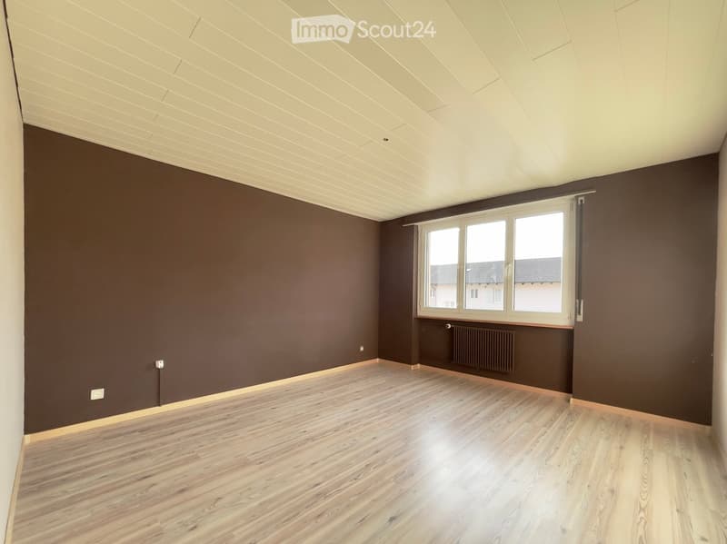 empty room, brown walls, wooden floor, white ceiling, a window with a radiator