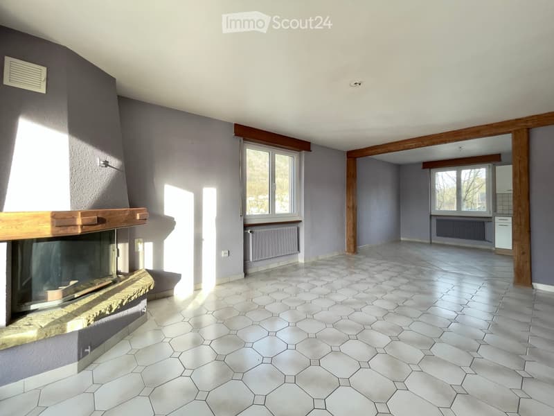 empty room with white hexagonal tiles, large fireplace, wooden beams, windows