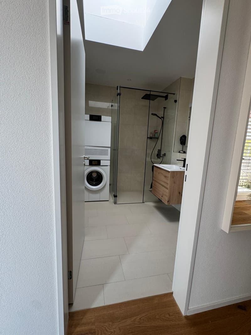 large white tiles, white walls, white door, washing machine, shower area, wooden sink, skylight
