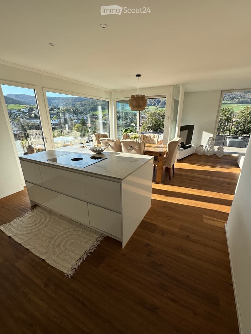 modern kitchen with island, large windows, balcony, dining table, living area with couch, TV, rug, wooden floor