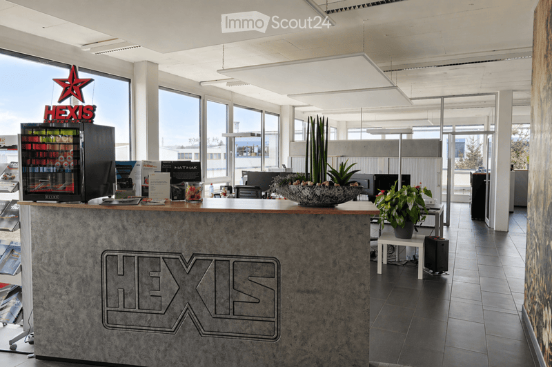 Modern office reception area with a marble reception desk, a refrigerator, potted plants, and office equipment.