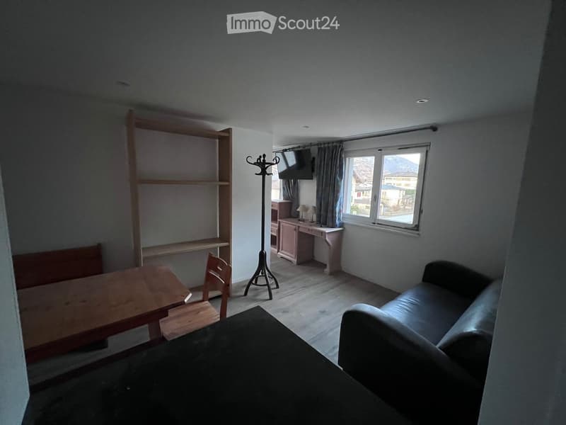 small room, wooden desk, small couch, wooden chair, wooden shelf, mounted TV, window