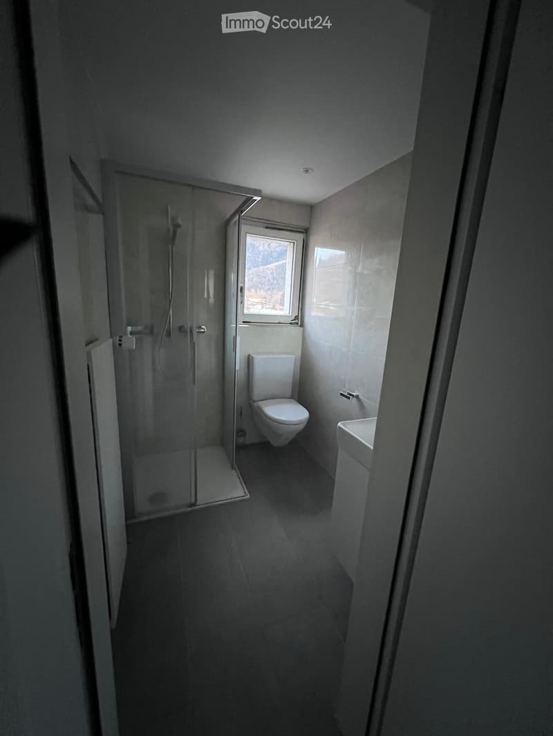 modern bathroom with glass enclosed shower, white toilet, white sink, tile flooring