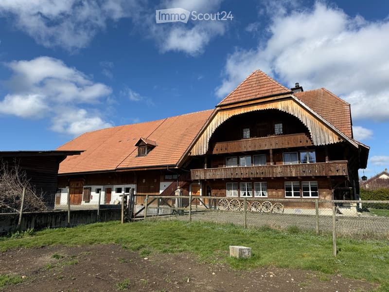 Traditional wooden house, red roof, wooden balconies, large windows, fenced yard, wheels in front
