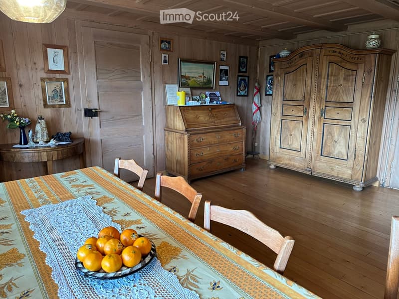 dining room with wooden floor, dining table, wooden cabinet, vintage tableware, picture frames, chandelier