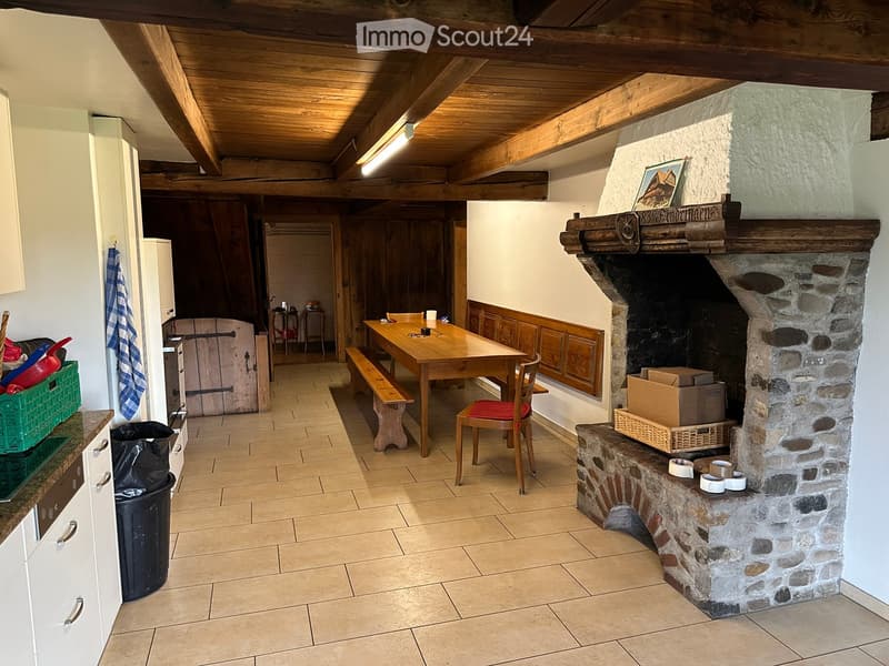 Fireplace, wooden beams, tiled floor, wooden dining table, wooden bench, chairs, kitchen appliances, trash can