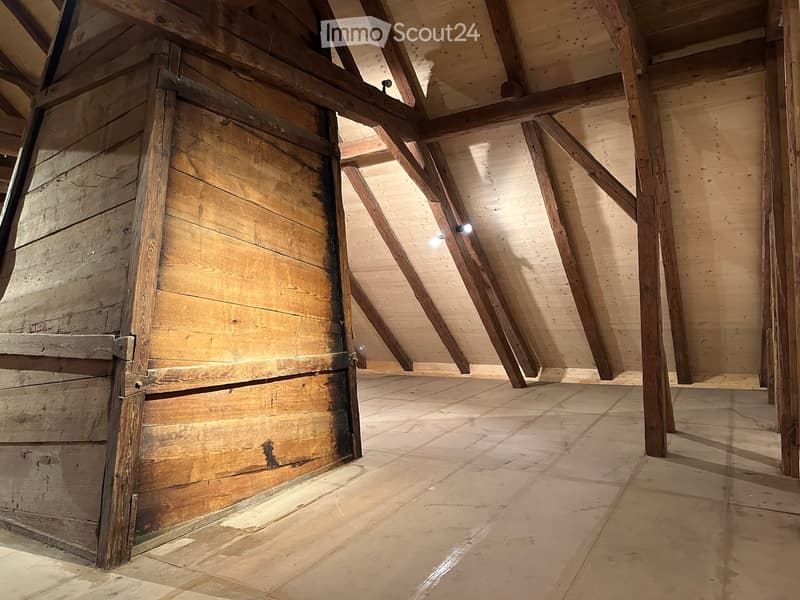 attic with wooden beams, wooden door, exposed rafters, tiled floor, mounted ceiling lights
