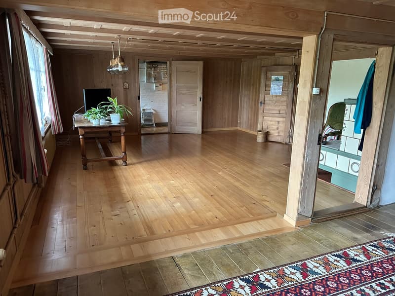 living room, wooden walls, hardwood floors, natural light, large windows, table with plants, small basket