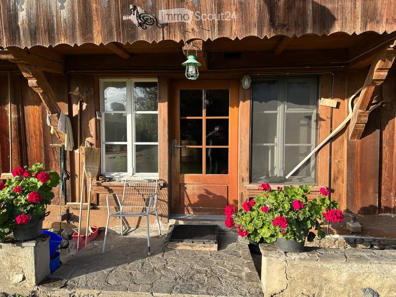wooden house with entry, wooden door, window, flowers, and chair