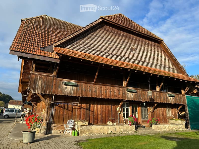 Large traditional wooden house, gable roof, large balcony, wooden pillars, garden in front
