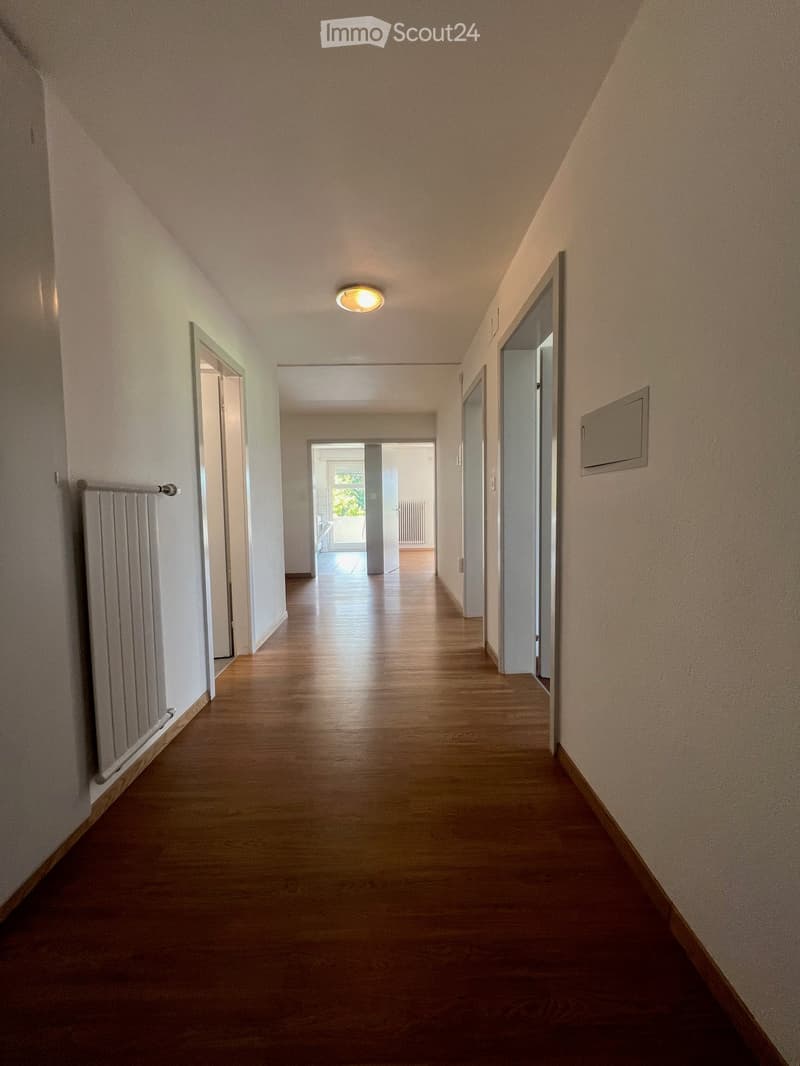 {"visible_features":[],"type":"Hallway","description":"The image shows a long, well-lit hallway with hardwood floors and white walls. There are several doors leading to other rooms along the hallway, and a recessed lighting fixture in the ceiling."}