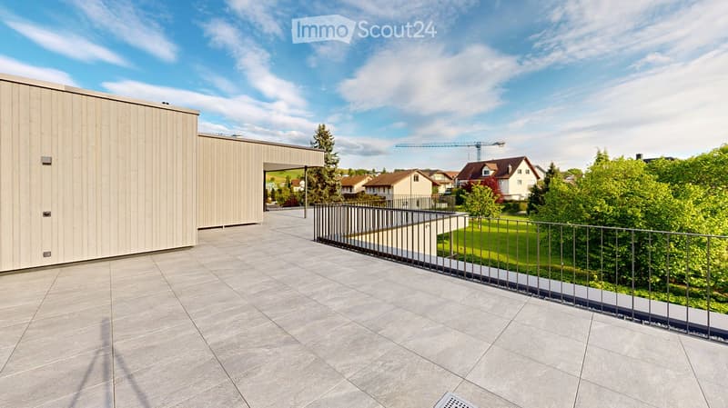 Modern balcony with grey tiled flooring, metal railing, and a view of a green lawn and neighboring houses.