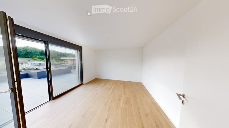 Empty room with light wooden flooring, white walls, and large sliding glass doors leading to a patio area.