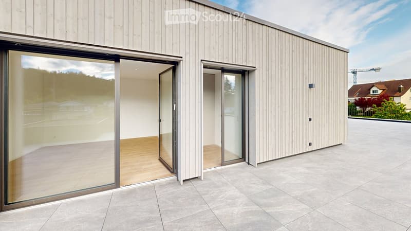 Modern building with light wood siding, large glass sliding doors, and a clean, minimalist design.