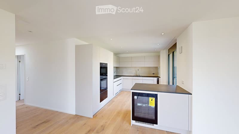 Modern kitchen with white cabinets, wooden flooring, built-in oven, dishwasher, and a central island with a countertop.