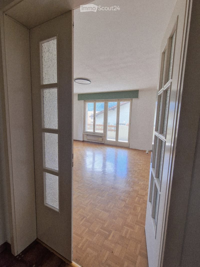 Empty room with wooden flooring, large windows, and a door leading to a balcony area.