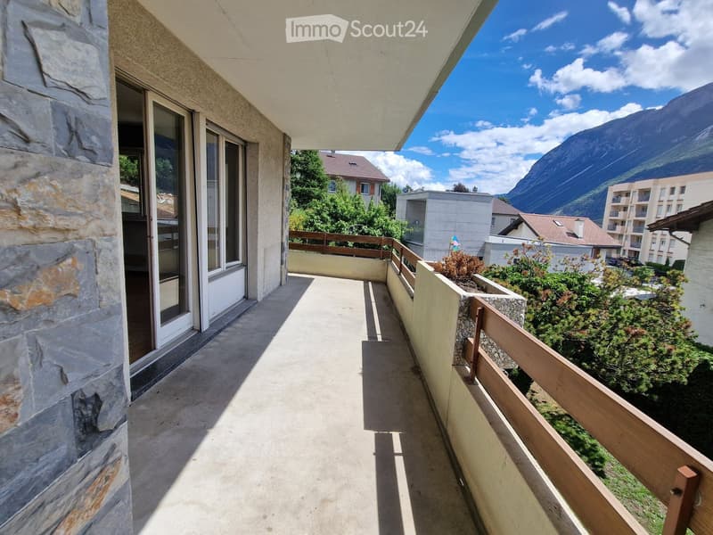 Balcony with stone walls, wooden railing, and scenic mountain view.