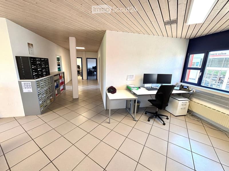 Office space with tiled floor, white desk, black office chair, computer, filing cabinet, and radiator under window.