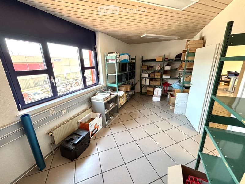 Office or storage room with tiled floor, large window, shelves filled with boxes and supplies, printer, radiator, and a laptop on the floor.