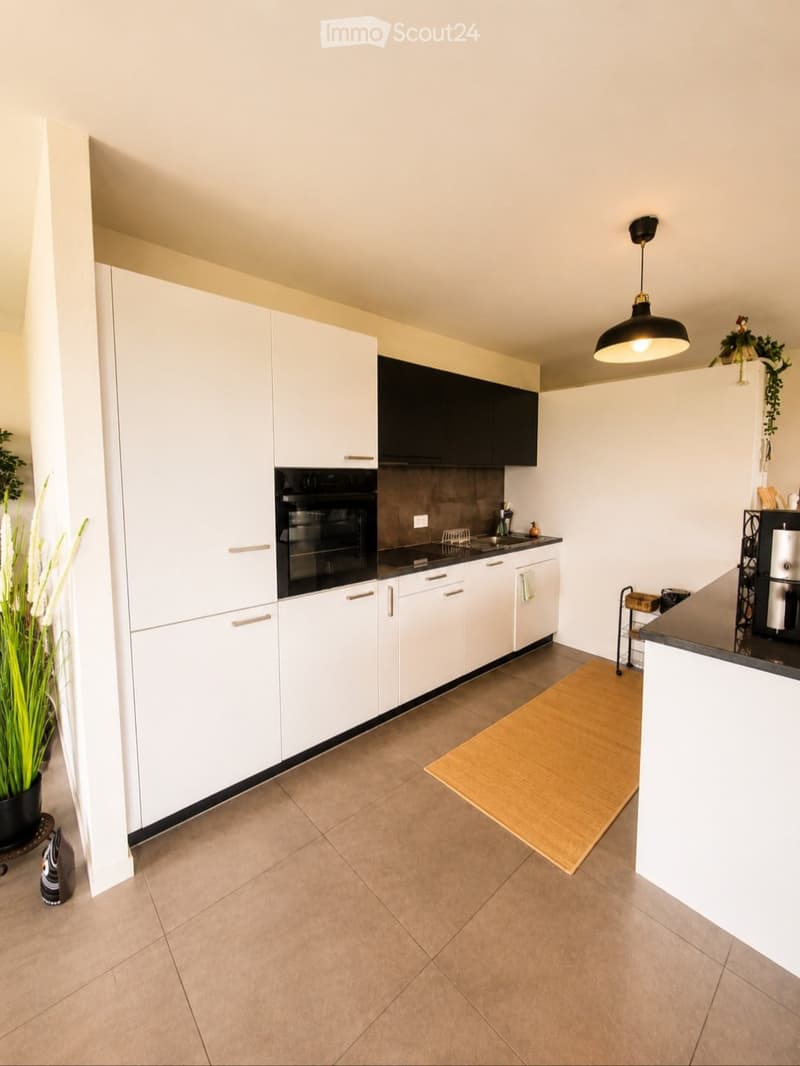 Modern kitchen with white cabinets, stainless steel appliances, a central island, and a pendant light fixture.