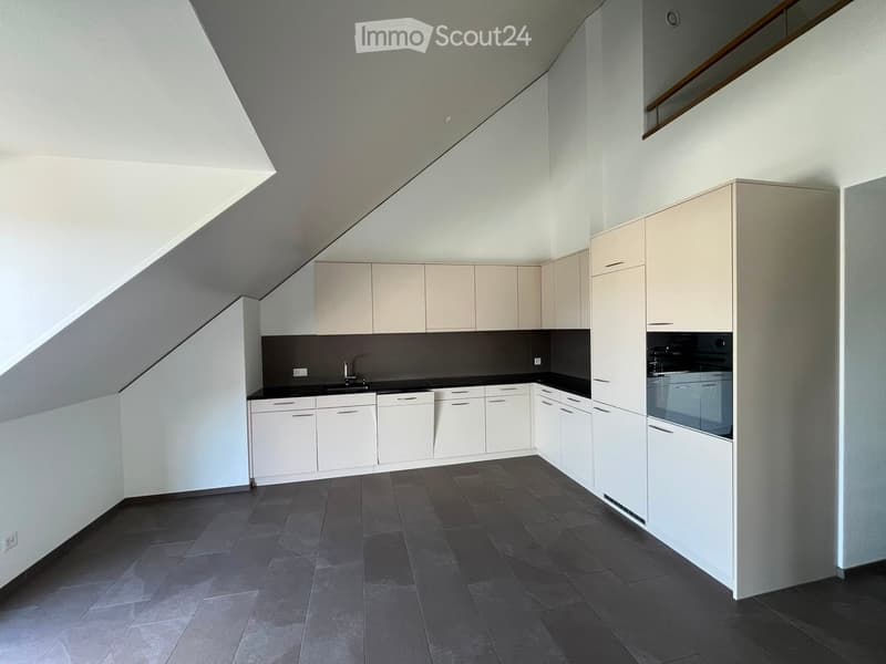 Modern kitchen with white cabinets, dark countertops, and a built-in oven. The space features a sleek design with a dark tiled floor and ample storage.