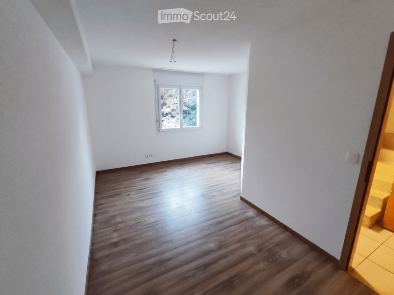 Unfurnished Room. Empty hallway with wooden flooring, white walls, and a window showing outdoor view. No furniture or equipment present.