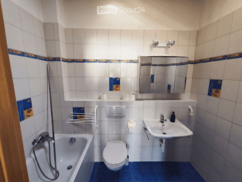 Bathroom. Bathroom with white tiled walls, blue accents, bathtub, toilet, sink, mirror, and towel rack.