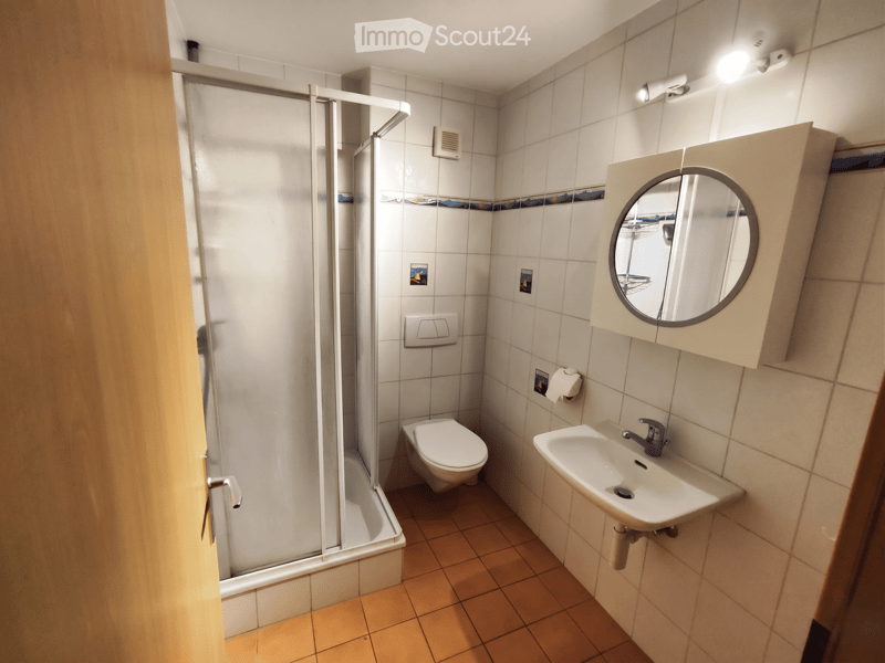 Bathroom. Modern bathroom with white tiles, a toilet, a sink with a mirror, and a glass-enclosed shower stall.
