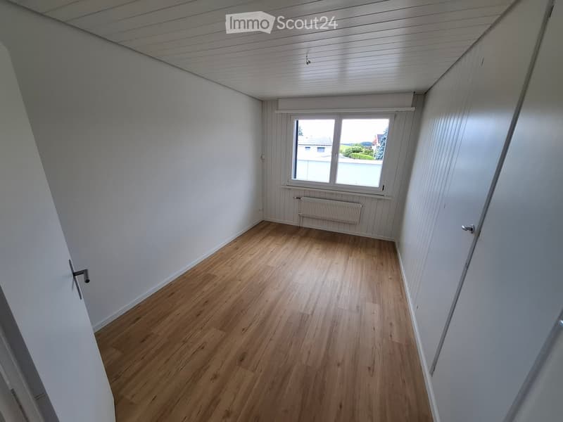 Empty room with wooden flooring, white walls, and a window with a view of the outside. No furniture or equipment is present.