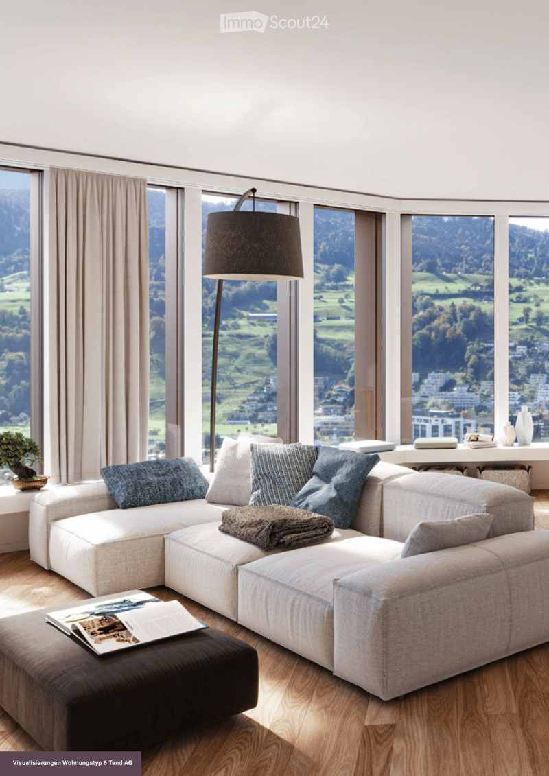 Living Room. Modern living room with large windows offering a scenic view, featuring a white sectional sofa, a dark ottoman with books, a floor lamp, and decorative vases on a side table.
