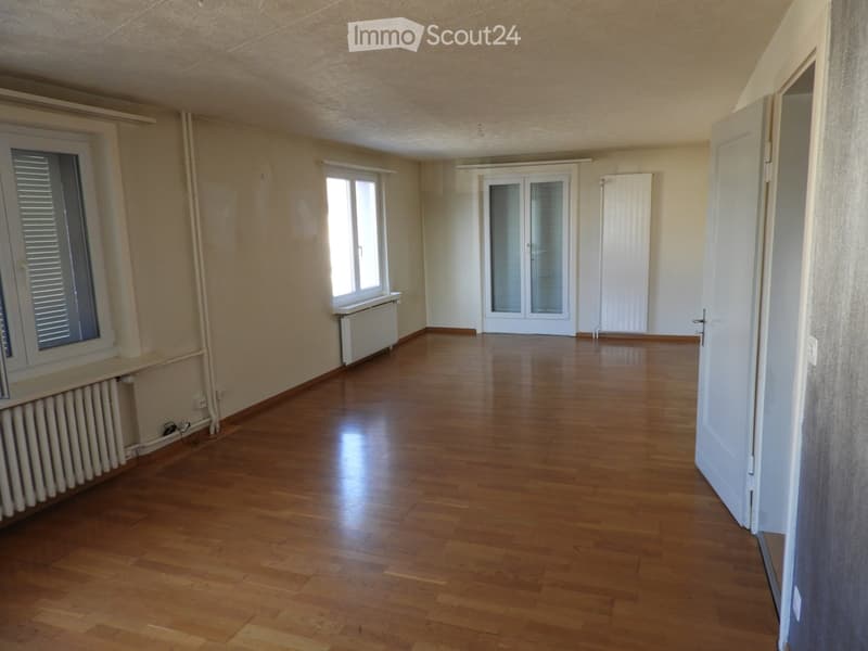 Empty room with wooden flooring, white walls, and large windows. No furniture or equipment present.
