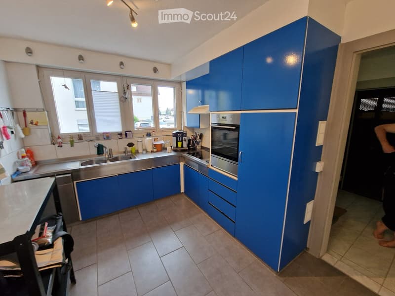 Modern kitchen with blue cabinets, stainless steel sink, oven, and various appliances on the counter.