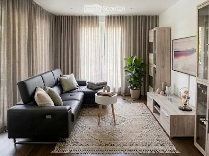 Modern living room with a black leather sectional sofa, wooden coffee table, side table, large plant, shelves, and decorative vases.